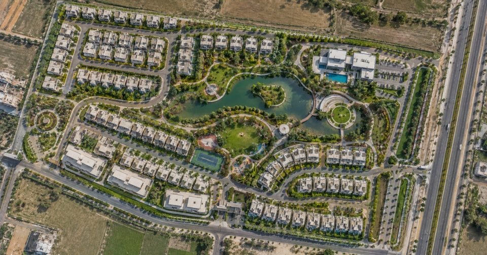Aerial view of a planned residential community with a central lake and landscaping
