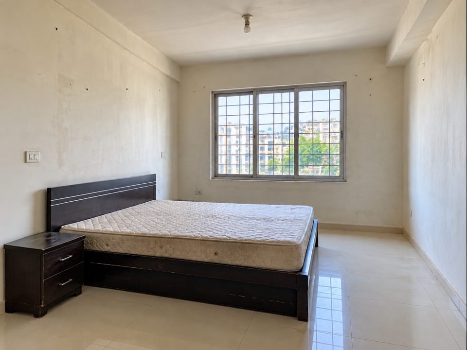 Bedroom before decoration with bare walls, a basic bed frame and a single ceiling bulb