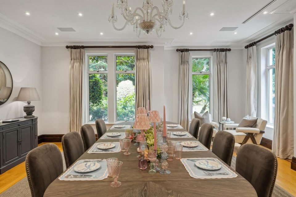 Classic dining room with floor-length drapes on tall windows, a crystal chandelier and a dressed table