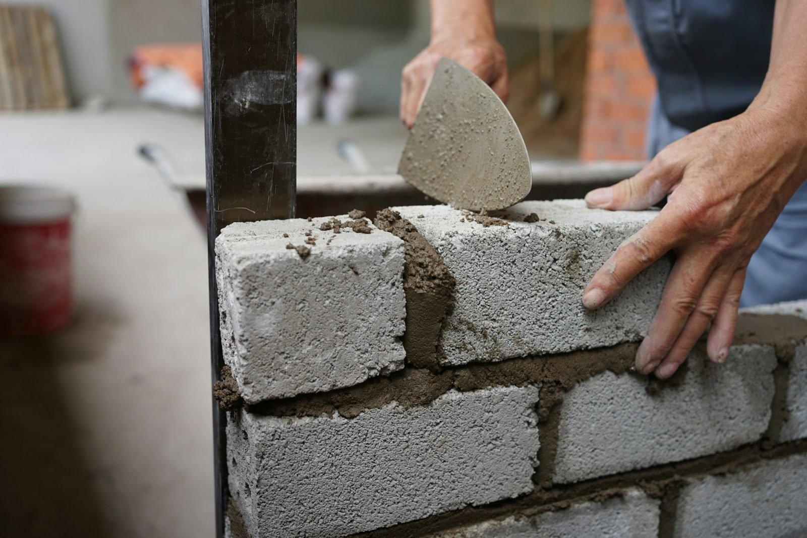 Hands laying concrete blocks with a trowel and mortar