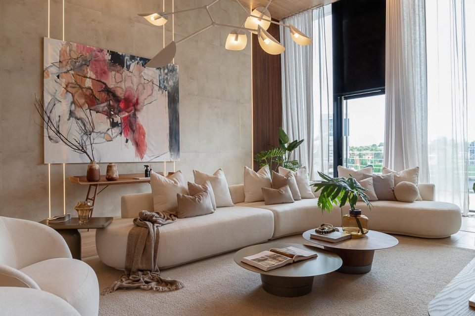 Living room styled with a large abstract painting, curved sofa and branch chandelier