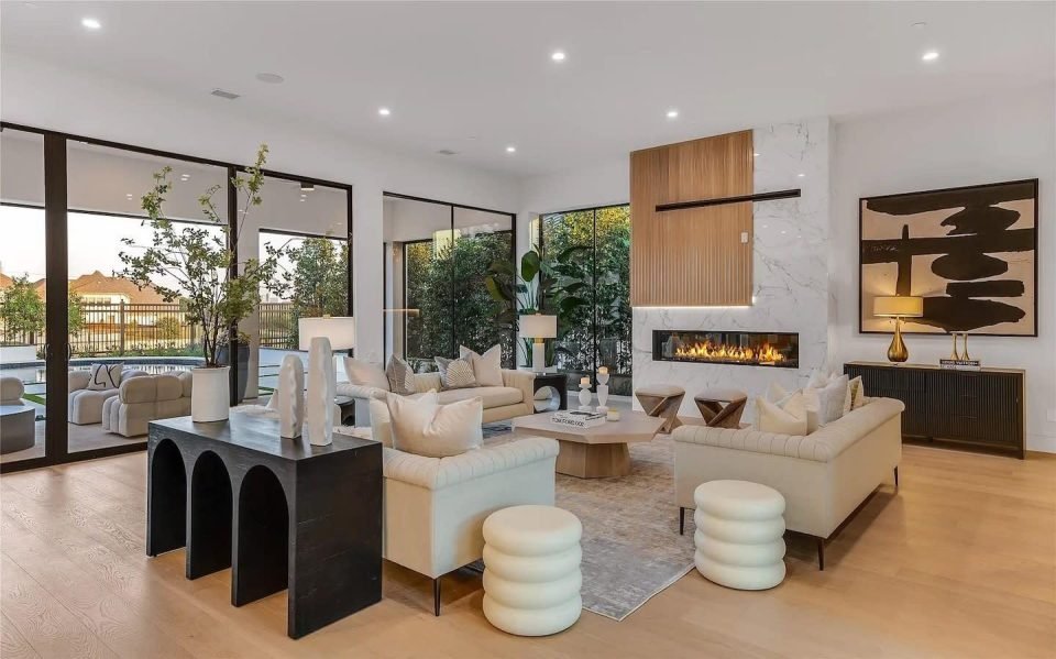 Living room styled with a fireplace, black console, bold artwork and boucle stools