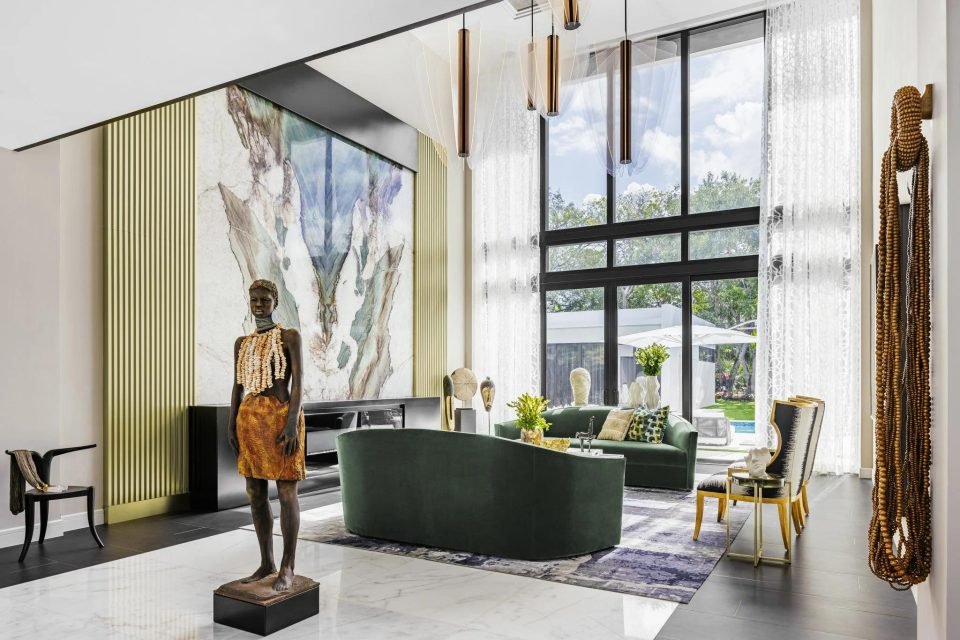 Double-height living room styled with a figurative sculpture, green sofa and marble feature wall