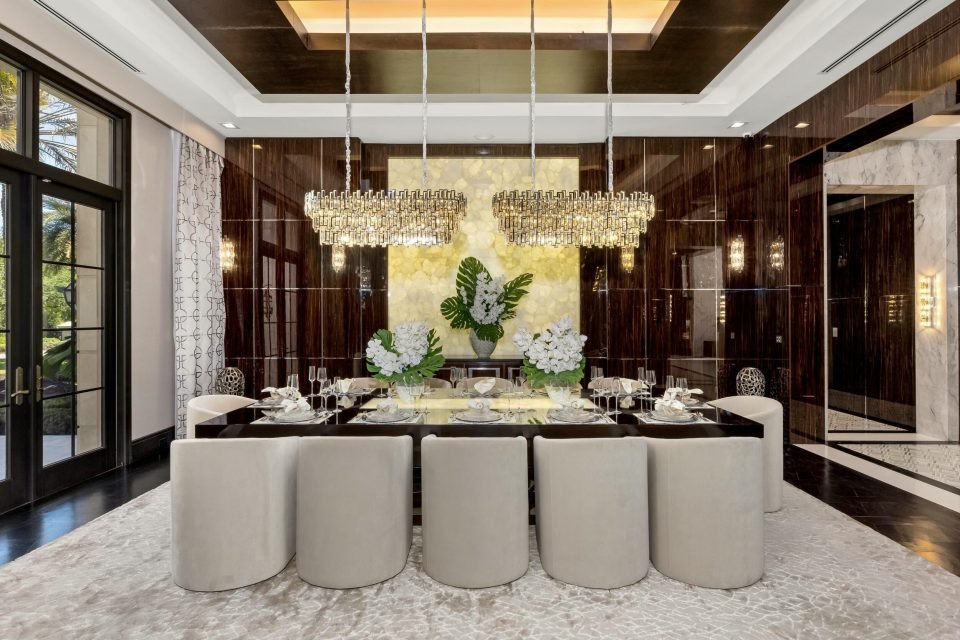 Formal dining room with twin crystal chandeliers, lacquered walls and upholstered chairs