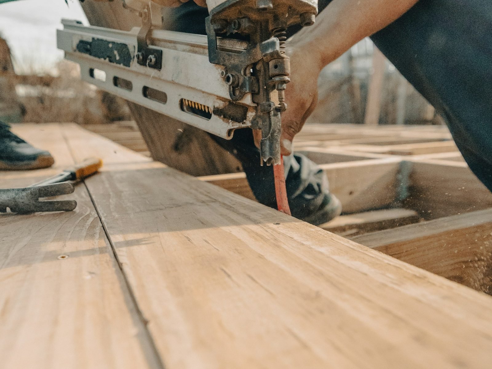 Worker fixing timber planks with a nail gun