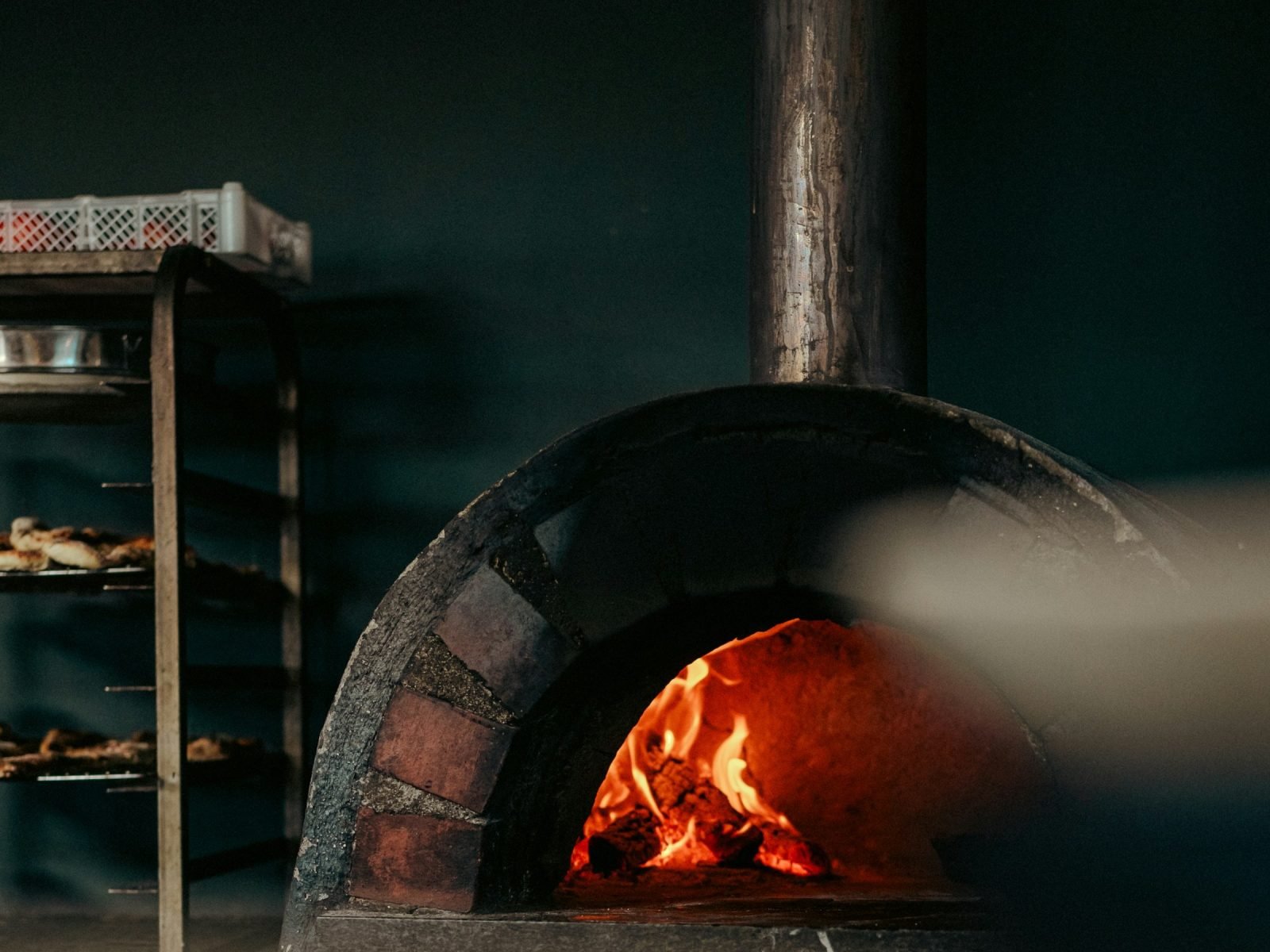 Brick pizza oven with a metal chimney flue above the mouth