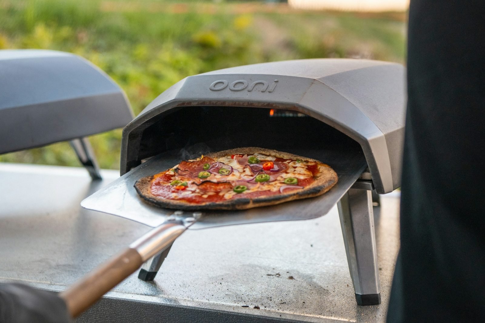 Portable outdoor pizza oven with a pizza on the peel
