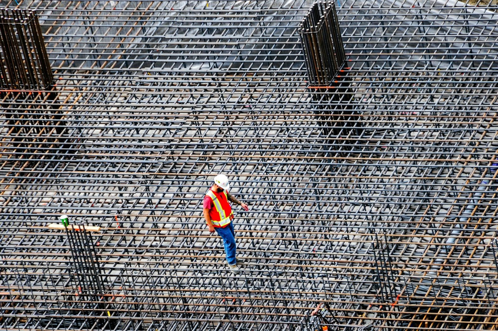 Worker checking a rebar grid laid out before a concrete pour