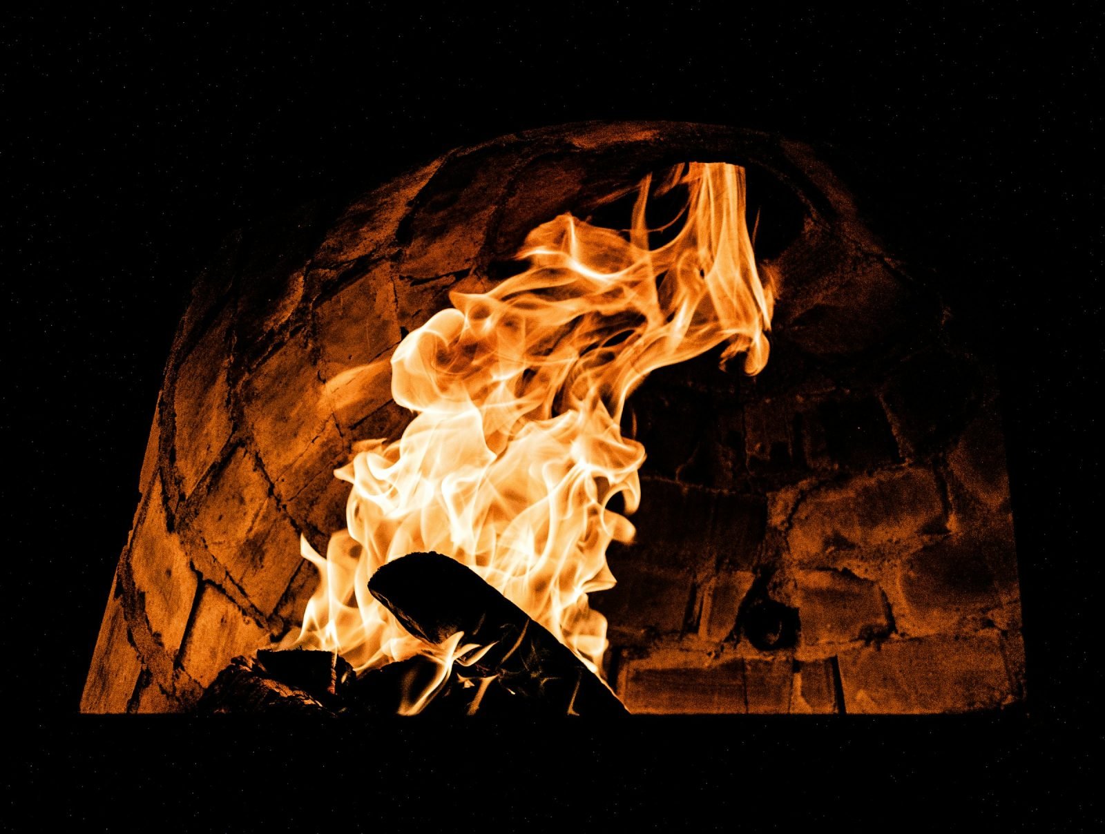 Small fire licking the inside of a brick oven dome