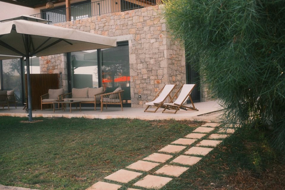 Stone-paved patio with loungers and stepping stones across a lawn