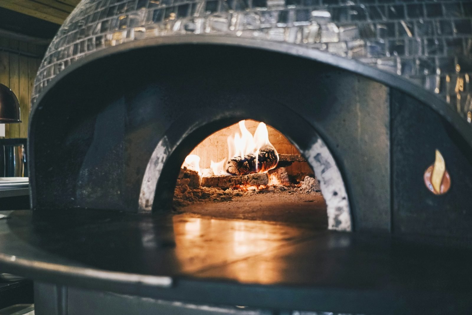 Dark tiled dome oven with a wood fire glowing inside