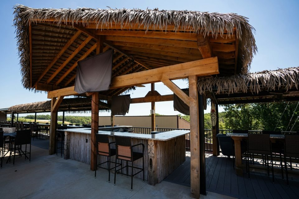 Timber outdoor bar with a thatched roof, bar stools and a counter