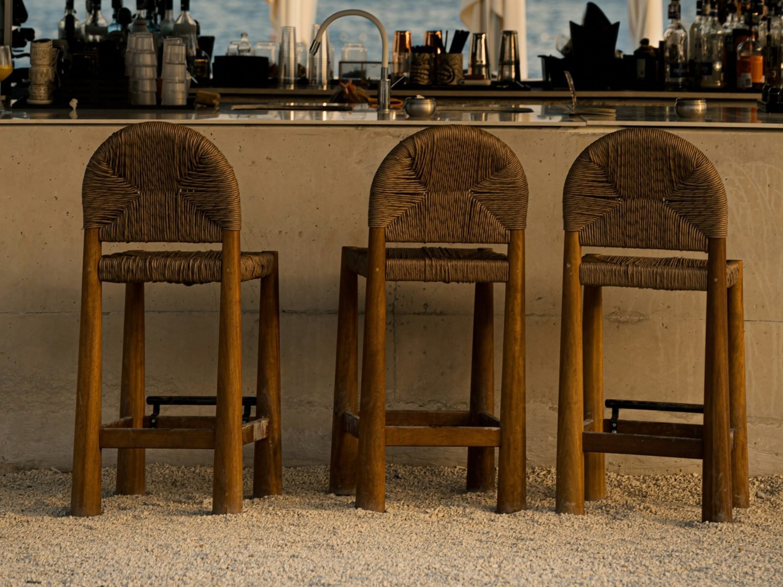 Row of woven bar stools at an outdoor bar